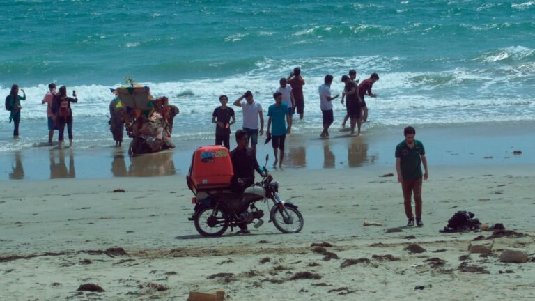 a group of people standing on a beach next to the ocean